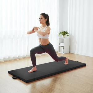 Woman performing a yoga pose on a black exercise mat in a bright room.