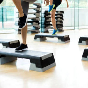 People exercising on step platforms in a gym setting