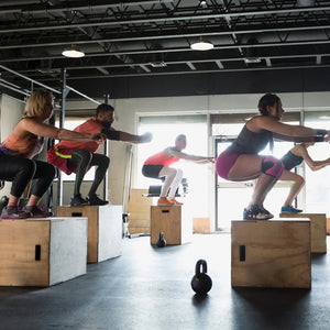 Group of people performing box jumps in a gym setting