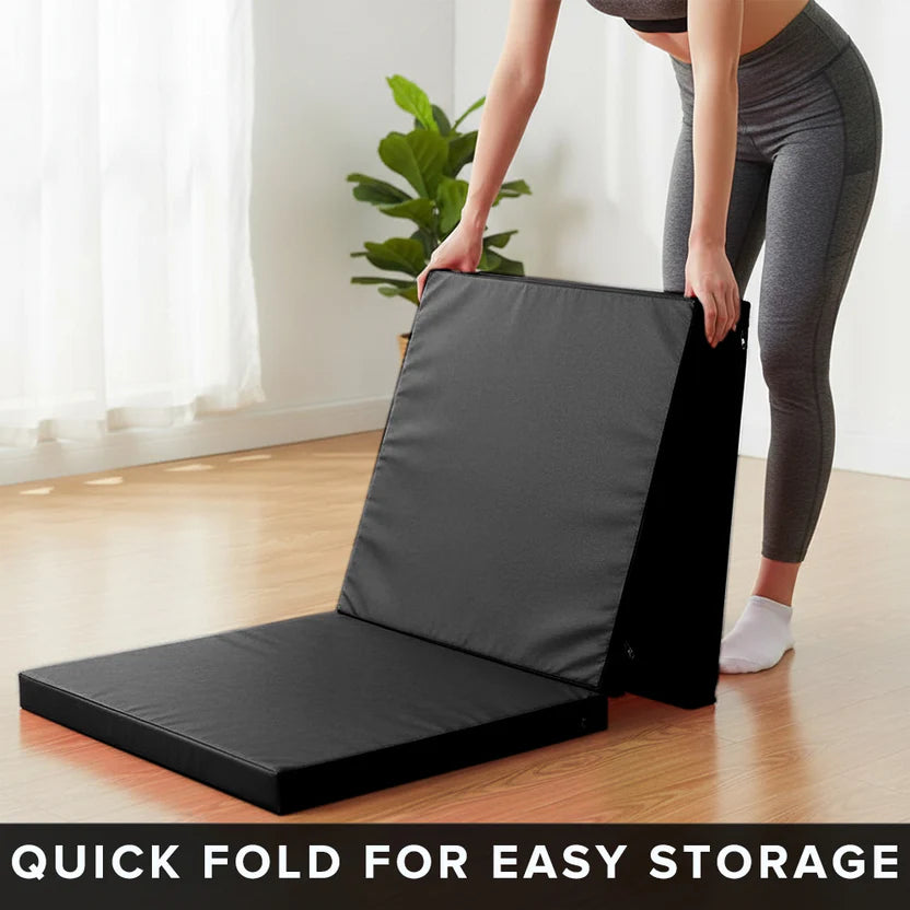 Person folding a black exercise mat with text 'Quick fold for easy storage' in a room with a plant.