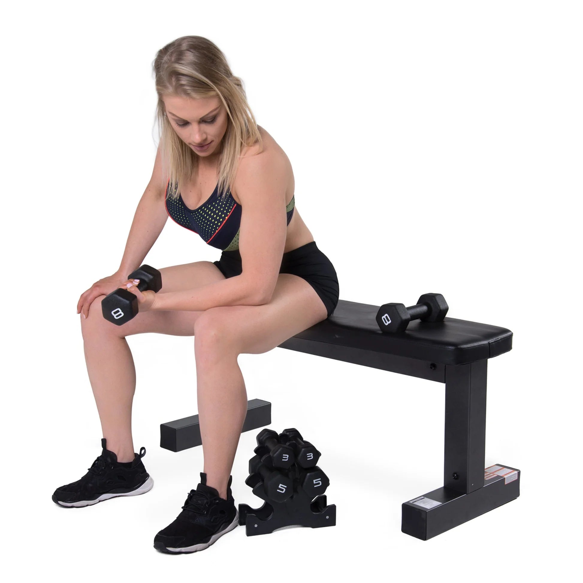 Woman exercising with dumbbells on a weight bench against a white background